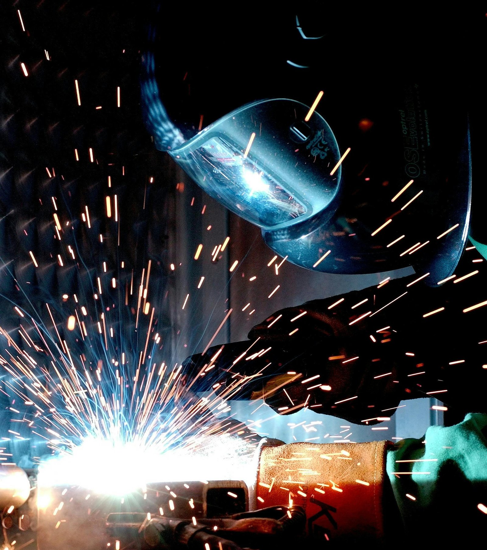 Metals A focused welder works with metal in an industrial setting, creating vibrant sparks.